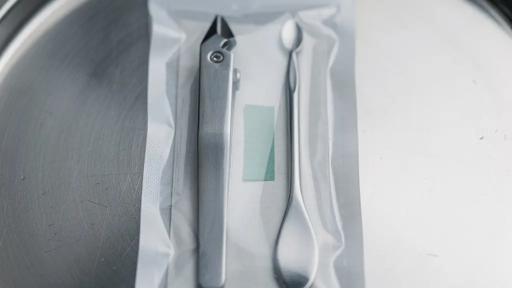 Extreme close-up of a sealed sterilization pouch showing an external process indicator and an internal indicator strip behind metal manicure tools.