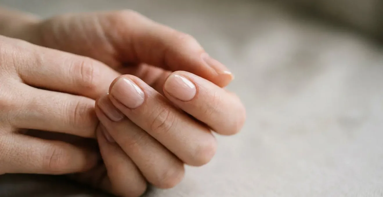 Close-up of hands with perfectly matched nude nail polish showcasing natural skin undertones in soft natural lighting